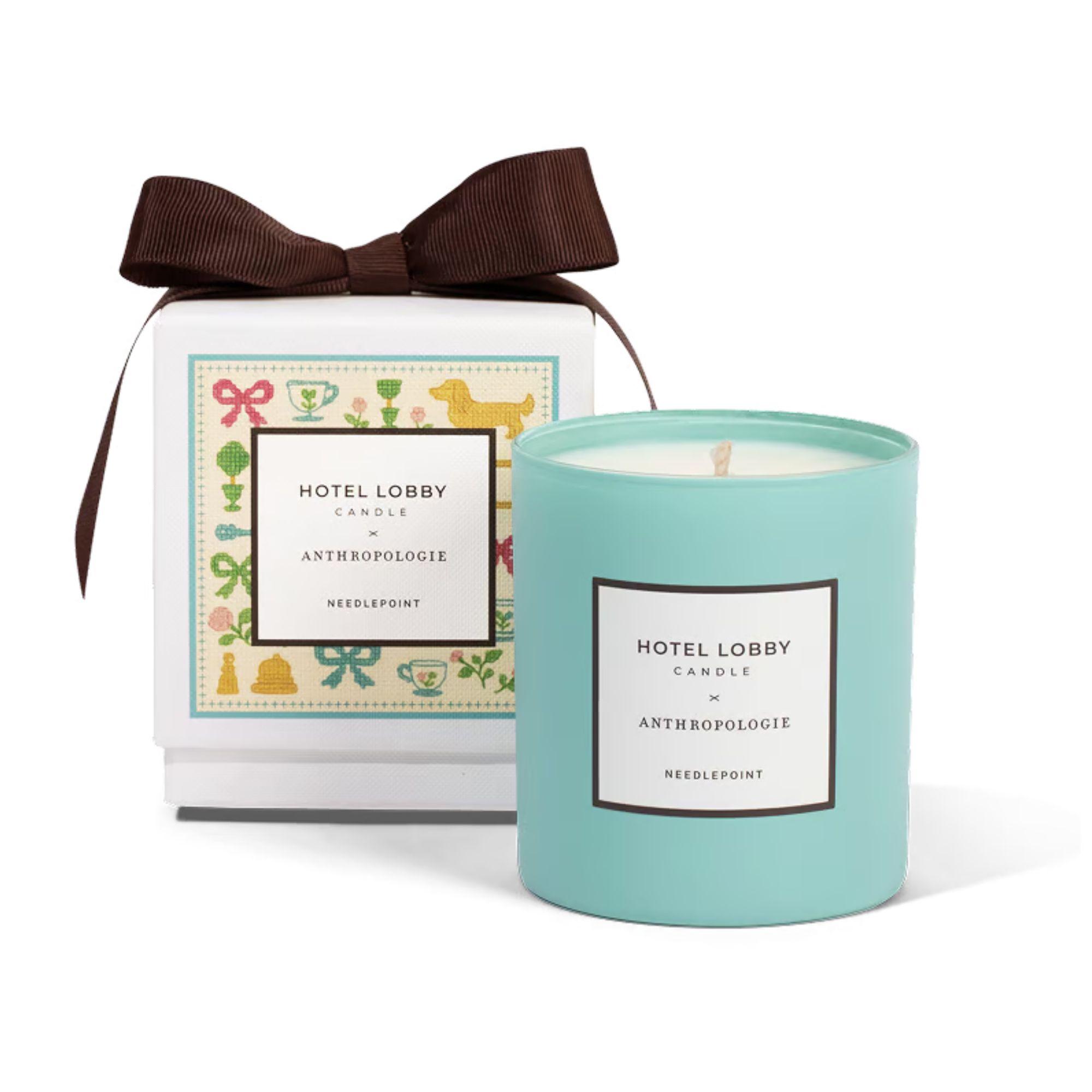 A blue Hotel Lobby x Anthropologie Candle with a white gift box decorated with colorful bows, bells, mugs, flowers, and dogs, with a large brown decorative bow on top.