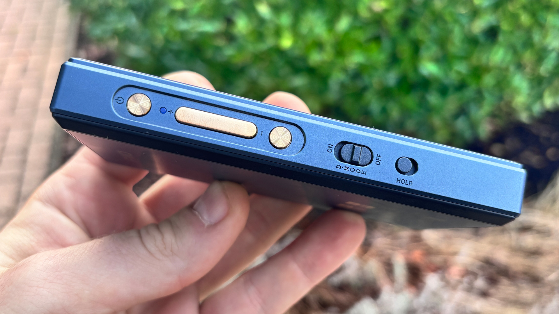 FiiO M21 portable music player held in hand sideways on showing controls