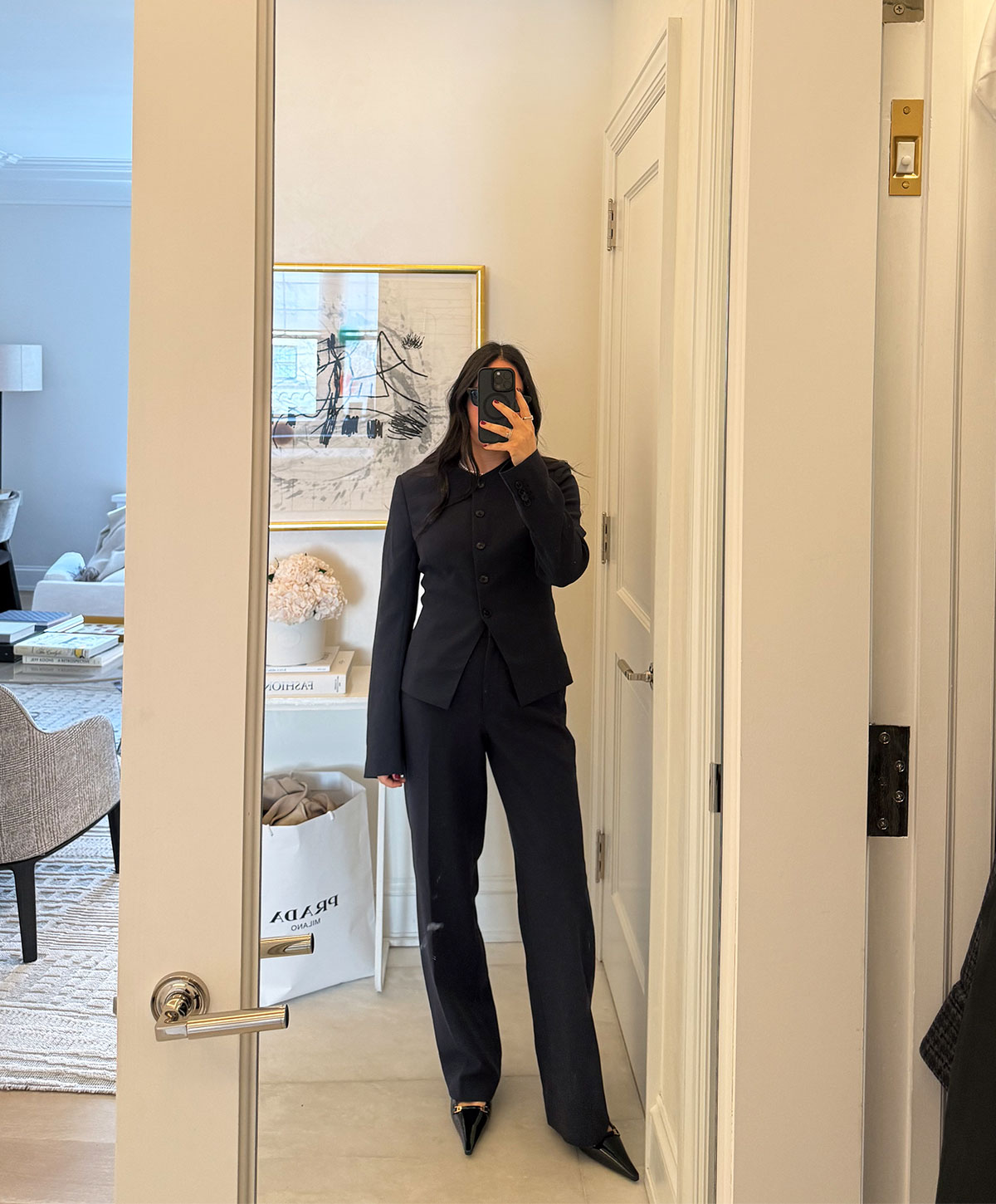 @nicoleakhtarzad taking a mirror outfit selfie and wearing an Aritzia navy blue suit.