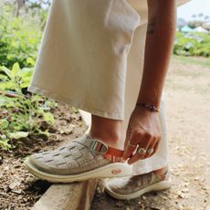 Woman adjusting beige Chaco sandals on a walking trail