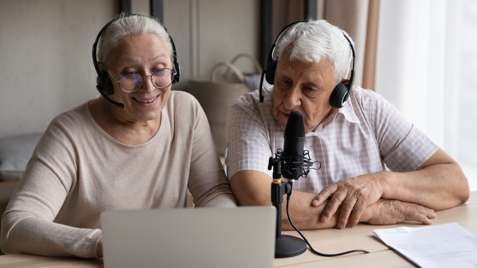 Joyful focused old couple recording voice at home