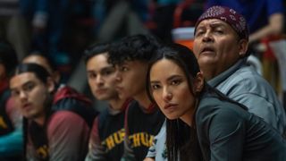 Cast members of Netflix&#039;s Rez Ball sit on the side lines of a basketball court observing a game