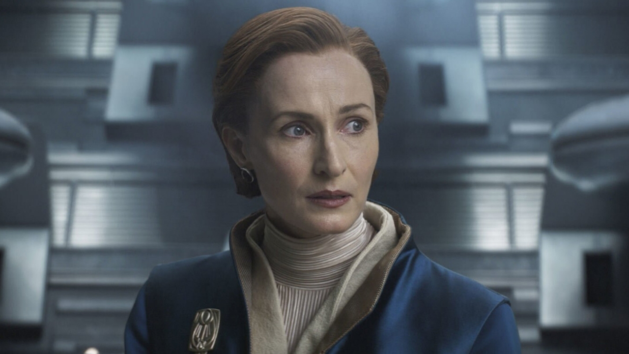 A red-haired lady in a blue suit stood in a futuristic room.