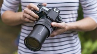 A pair of hands holding the Sony RX10 IV