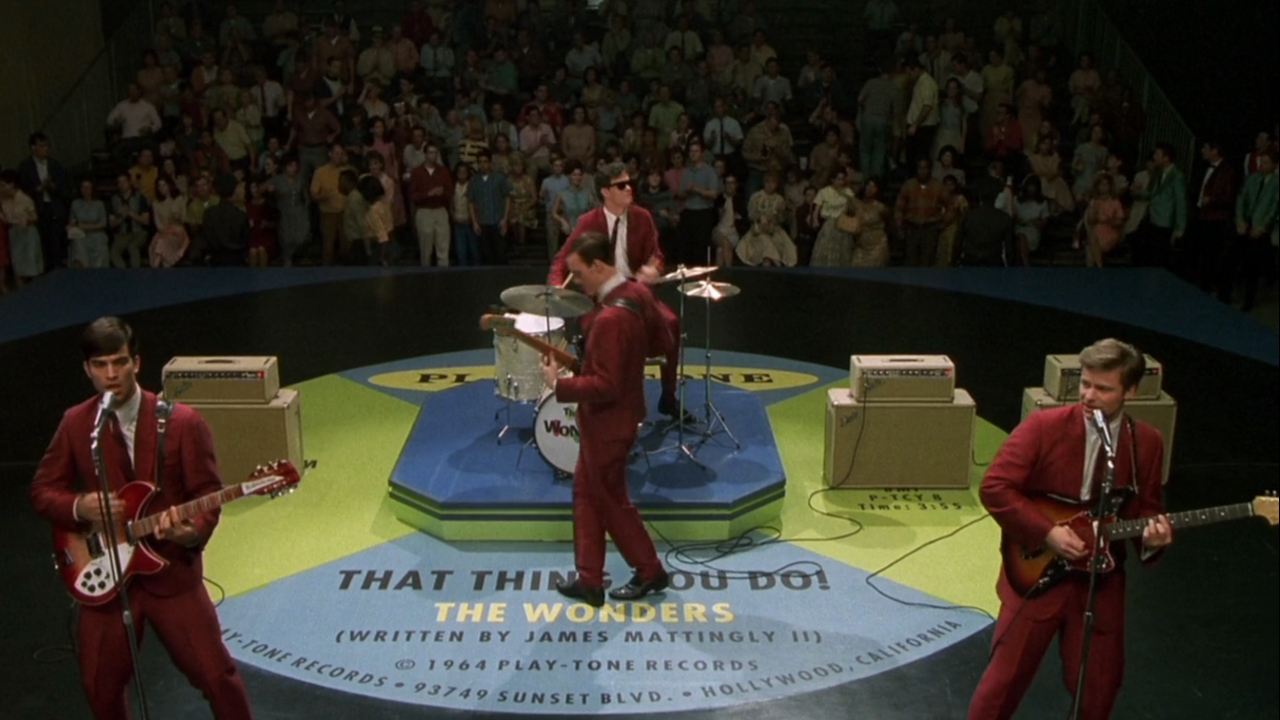 Johnathon Schaech, Tom Everett Scott, Ethan Embry, and Steve Zahn perform on a giant vinyl graphic in That Thing You Do!