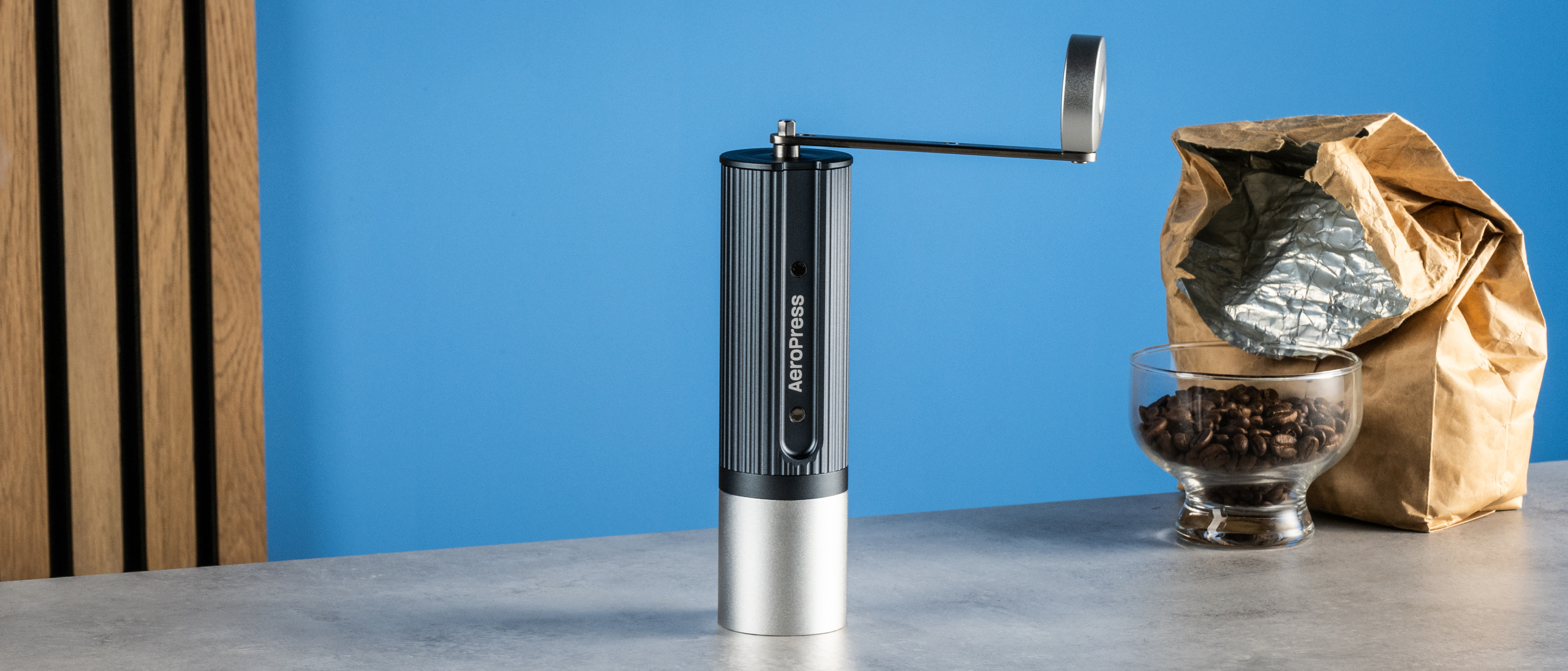 the aeropress manual coffee grinder in gray and silver against the tom's guide blue background