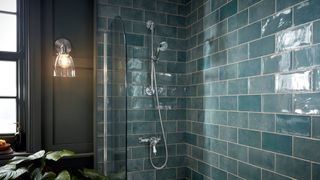 Shower area with blue metro tiles and wall-mounted lighting