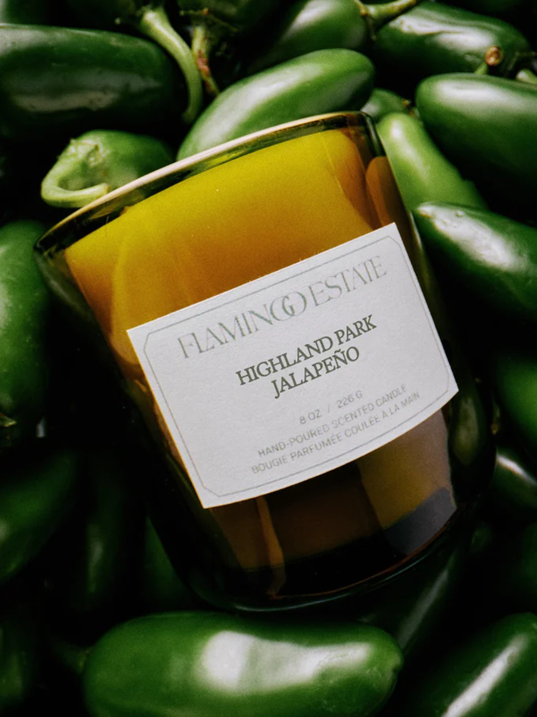 A glass candle in a bowl of jalapenos