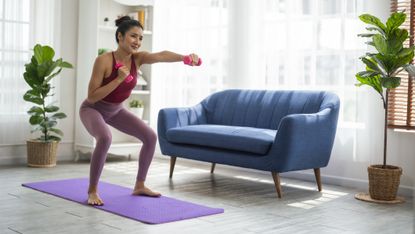 Woman exercises at home with small dumbbells