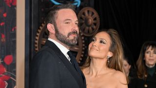 JLo looking up at Ben Affleck in a suit and smiling while they posed on the carpet of This is Me... Now: A Love Story" premiere.