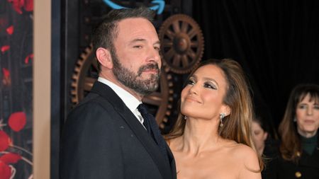 JLo looking up at Ben Affleck in a suit and smiling while they posed on the carpet of This is Me... Now: A Love Story" premiere.