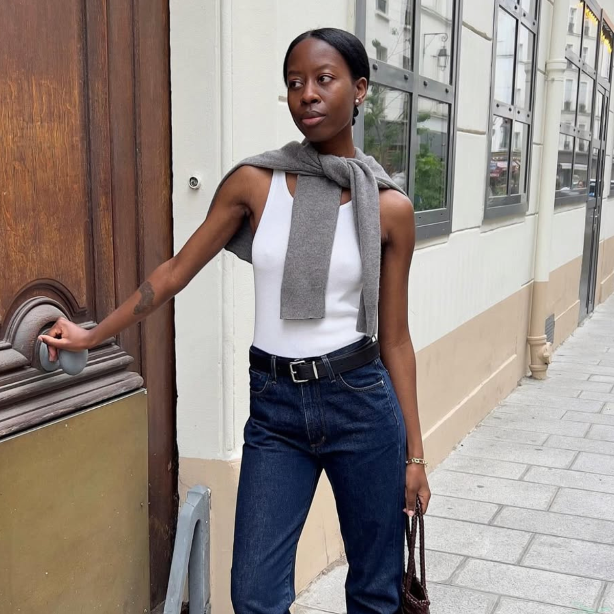 Sylvie in dark wash jeans, white vest and grey jumper