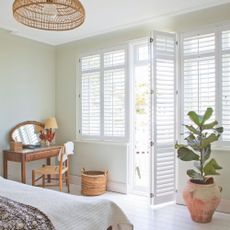 White painted bedroom with white shutters on the windows and doors