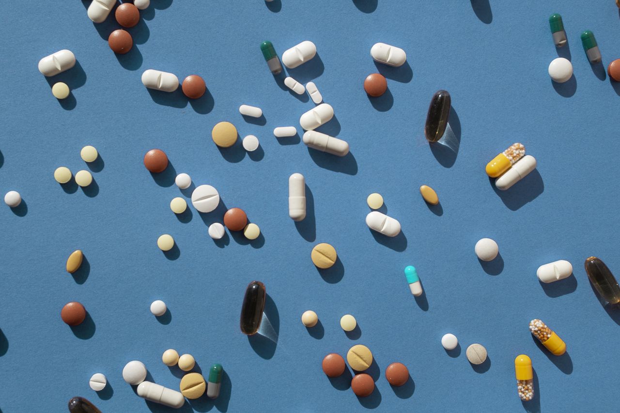 different kinds of pills spread out across blue background