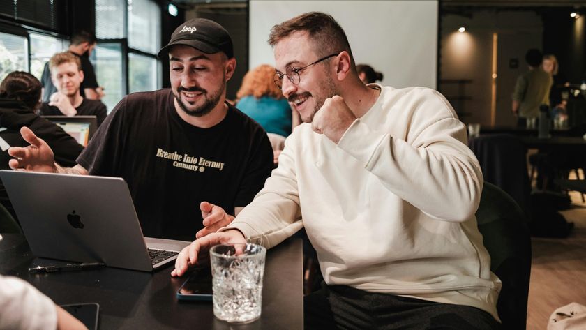 Two men using laptop in crowded cafe