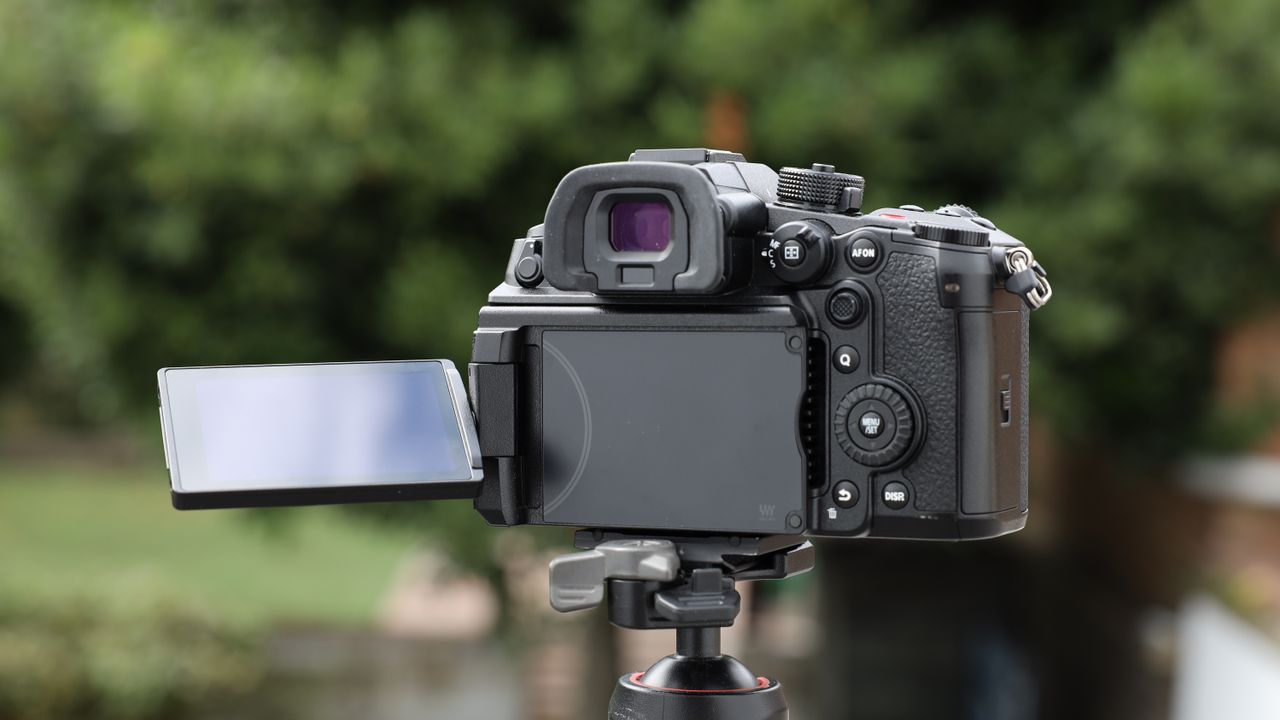 Panasonic Lumix GH7 on a tripod outside with some blurred green trees in the background