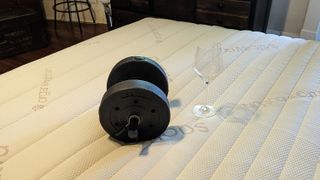 A dumbbell and a wine glass on the Saatva Memory Foam Hybrid mattress