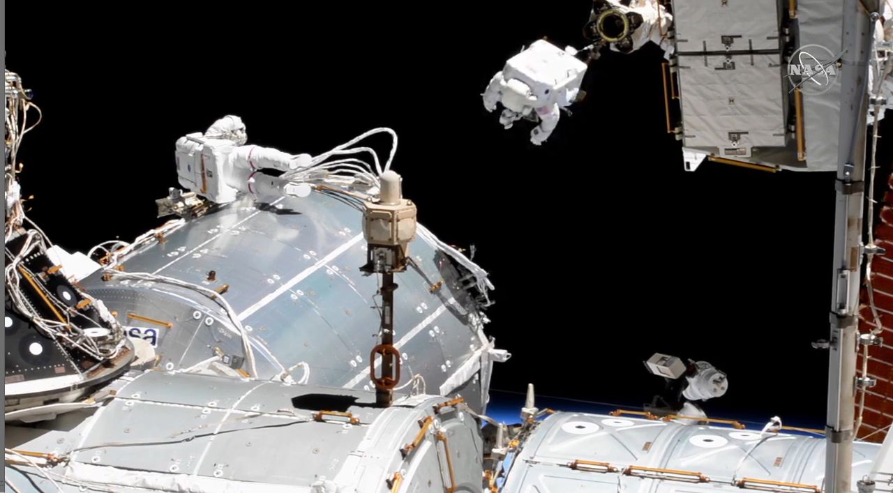 Astronaut Victor Glover rides the Canadarm2 robotic arm outside the International Space Station while crewmate Michael Hopkins of NASA works nearby in a spacewalk on Jan. 27, 2021.