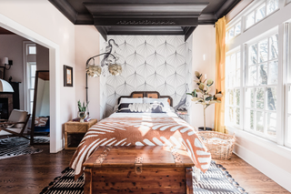 bedroom ideas with wallpaper behind the headboard and a patterned quilt under a black ceiling