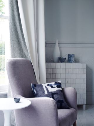 armchair and side table beside window with curtain with patterned lining