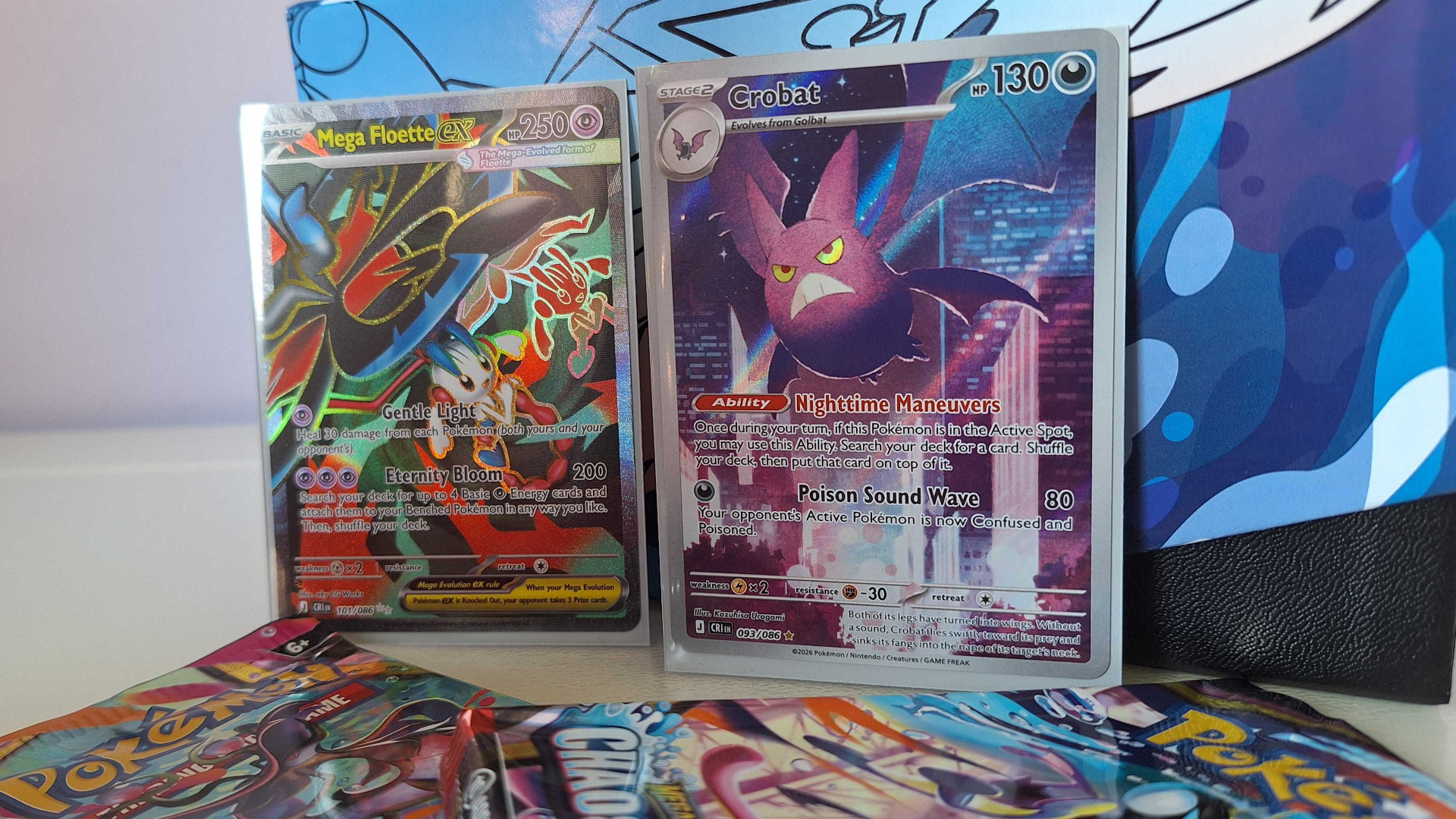A Golbat and Mega Floette ex card against a Chaos Rising Elite Trainer Box, with boosters visible in the forground