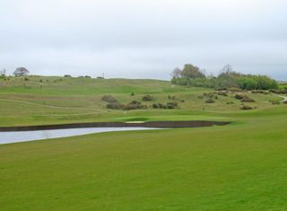 The thirteenth green with the par-3 fourteenth beyond it on the side of the hill