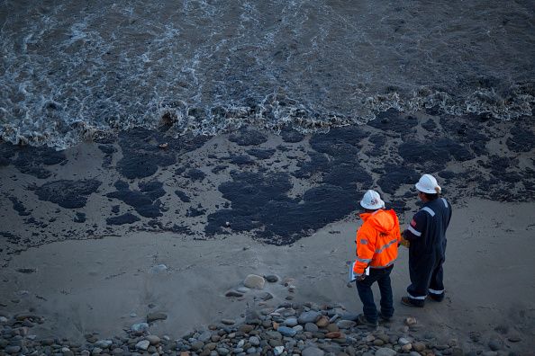 Clean up workers look at oil in the water.