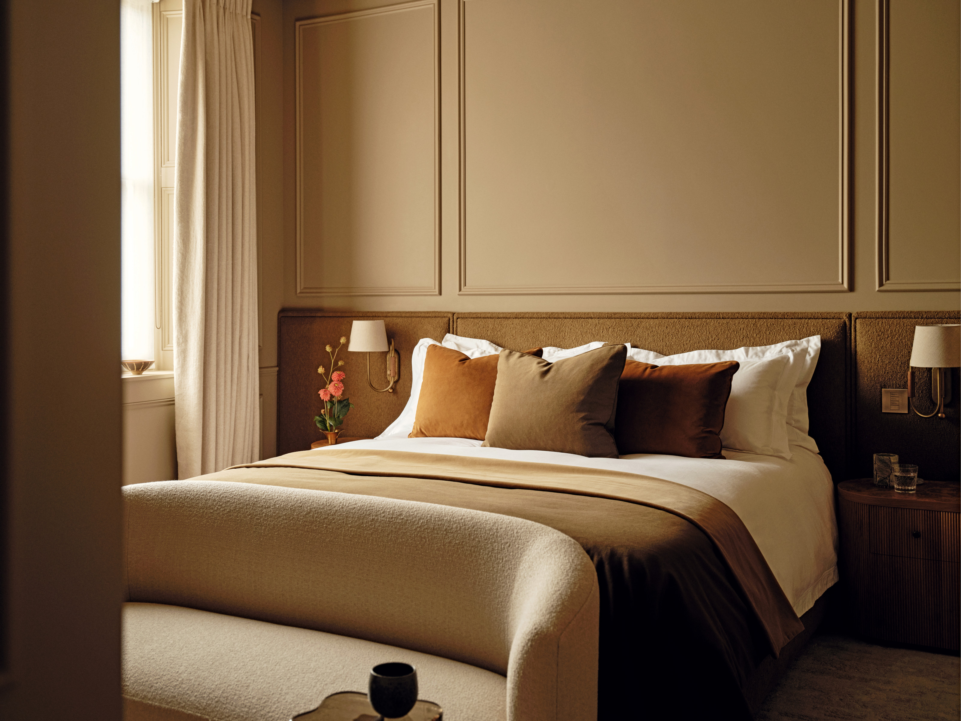 Beige bedroom with panelling, extended headboard and bench at the end of the bed