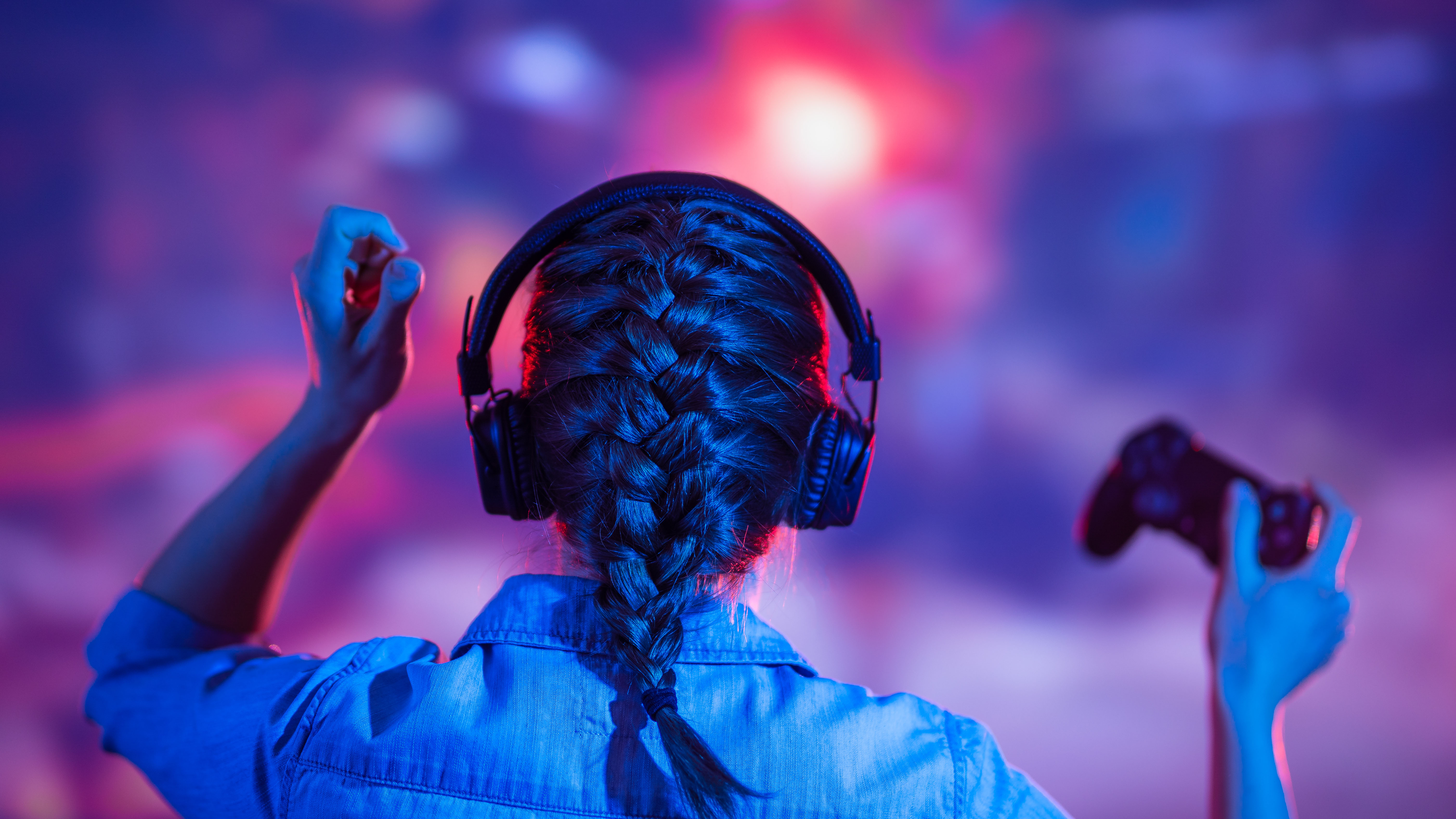 young girl sits in front of screen with headset and controller