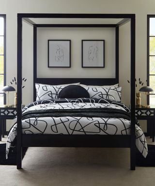 A black and white monochromatic bedroom with four-poster bed with framed wall art decor above bed