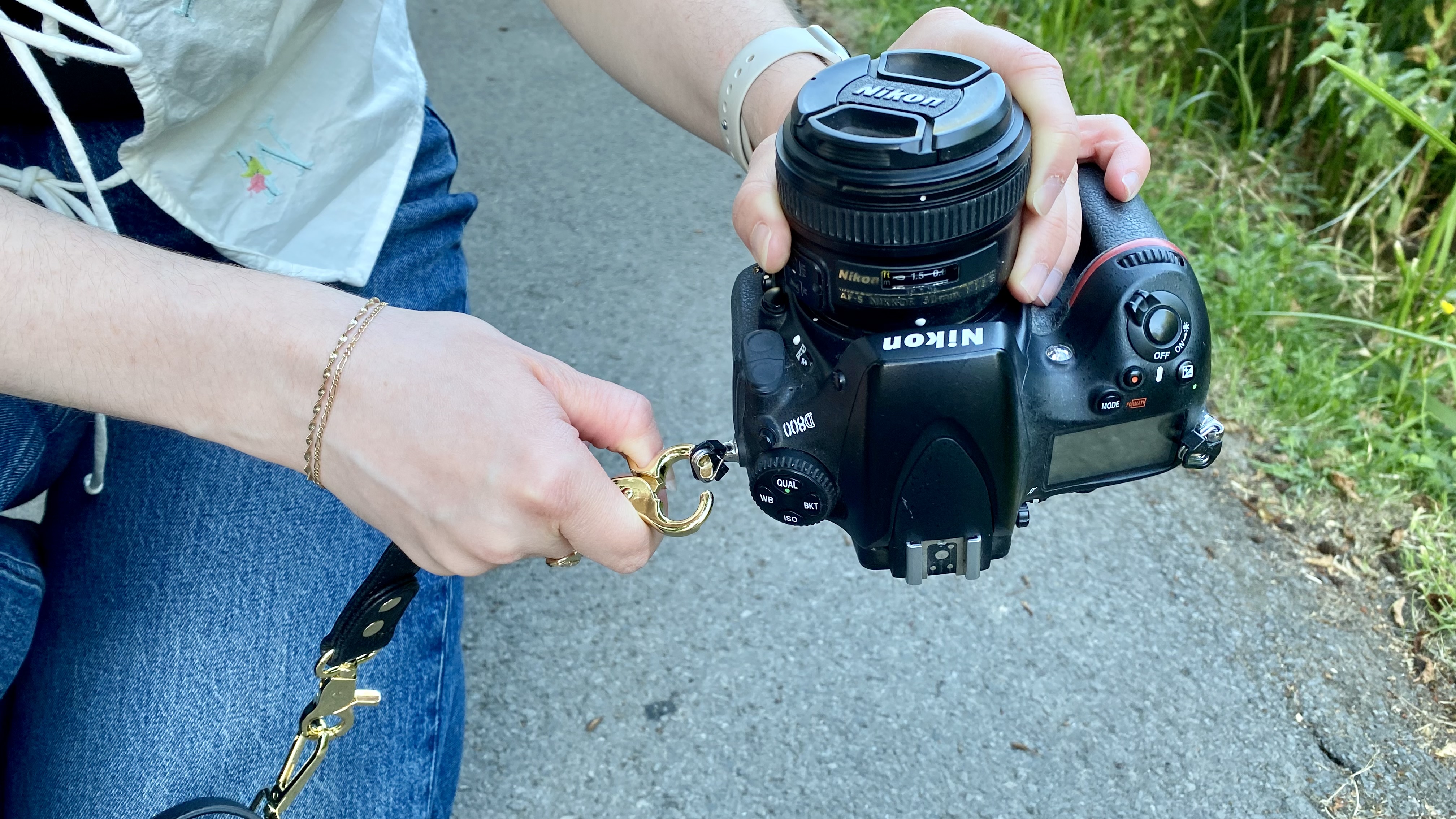 Person attaching Voygr 1 camera bag strap to a camera