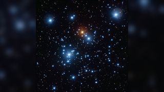 Several bright blue stars of varying size surround a bright large orange star.