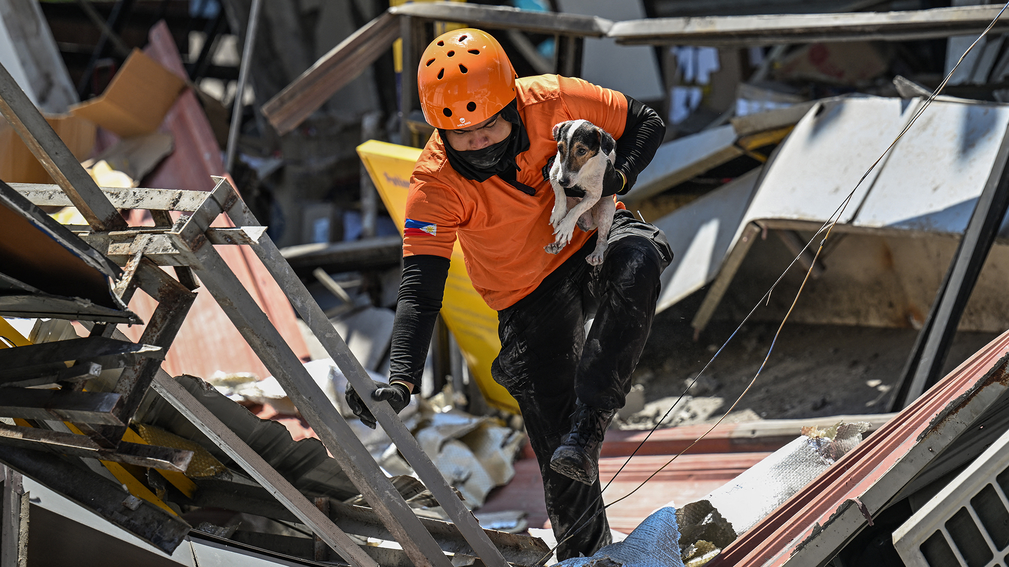A responder carries a dog while conducting search and rescue operations in a collapsed building after a 7.8 magnitude earthquake in General Santos City, Philippines