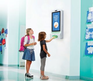 Two students using the Clear Digital Gel Sanitizer