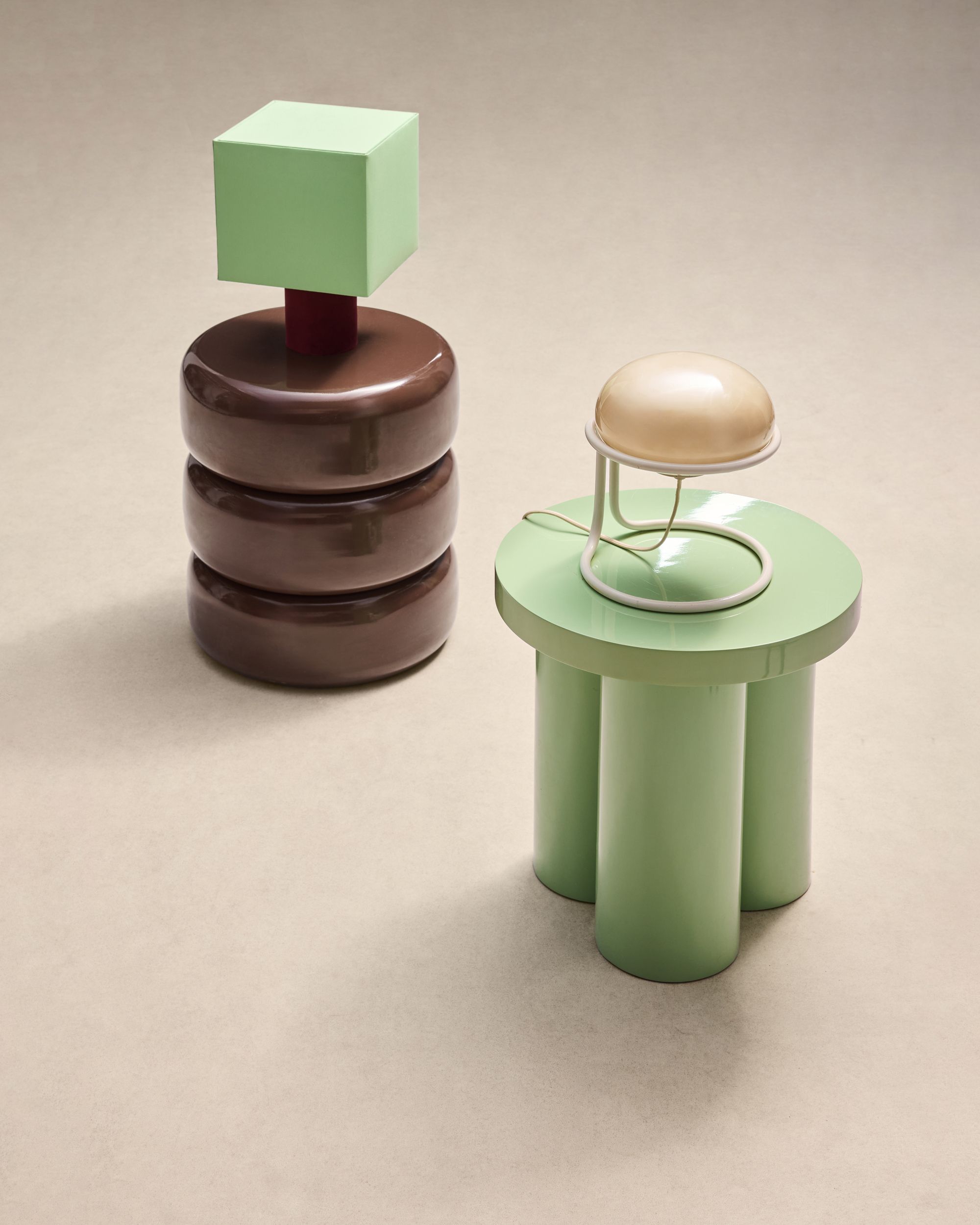 Image of two modern, high-gloss accent tables (one mint green and one brown) each with a modern table lamp on them.