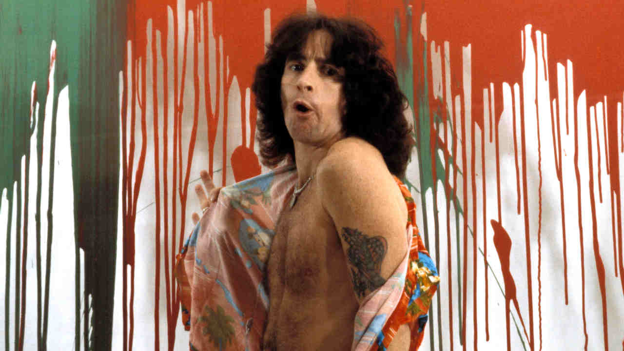 AC/DC&amp;rsquo;s Bon Scott posing for a photograph in front of a paint-splattered wall