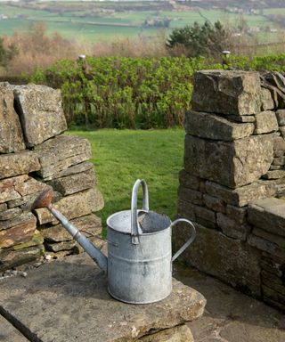 A watering can on a stone ledge in the countryside