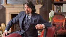 laurence llewelyn bowen sitting on red chair infront of fire place