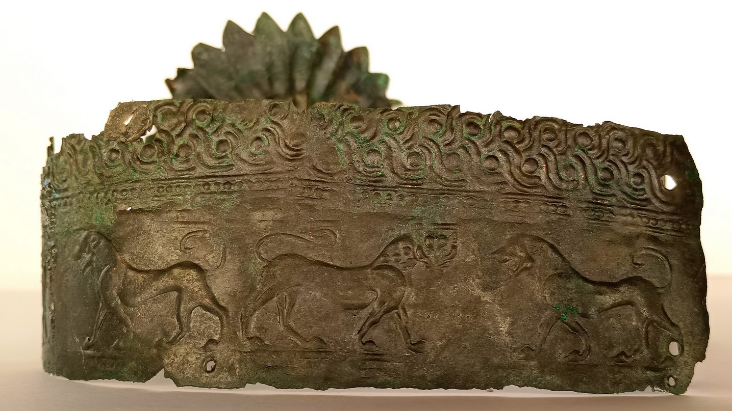 a bronze crown with stamped lions and a curly border