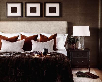A brown themed bedroom with a double bed dressed with comfy cushions and a brown faux fur blanket