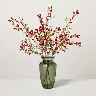 Faux Winterberry Stems Christmas Arrangement in a vase against a gray background.