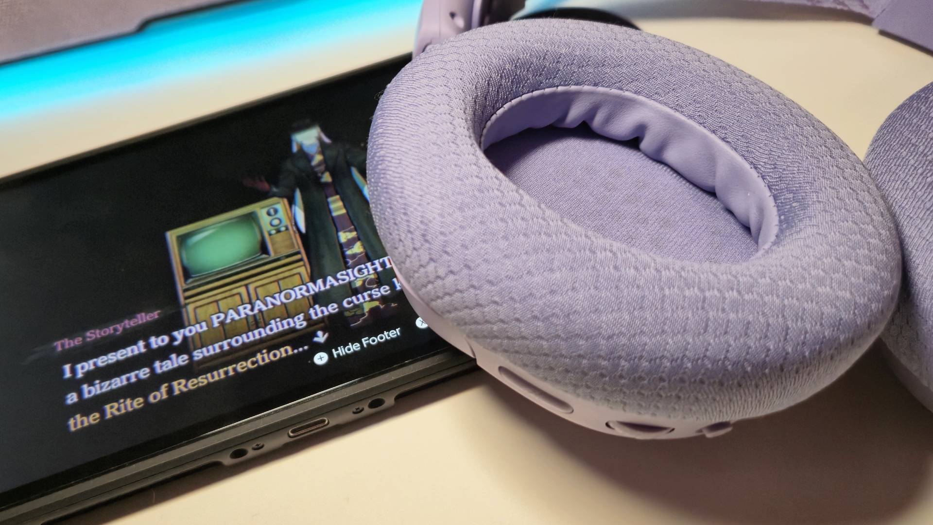 Photo of the purple cups of the Arctis Nova 3 Wireless sitting on top of a Switch 2 playing Paranormasight.