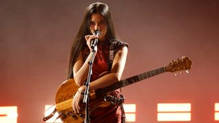 Nene Royal singing and playing guitar on stage