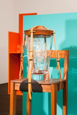 Glass vase strapped to a wooden chair