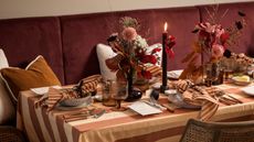Fall tablescape with striped brown and cream tablecloth, matching napkins, and amber glassware