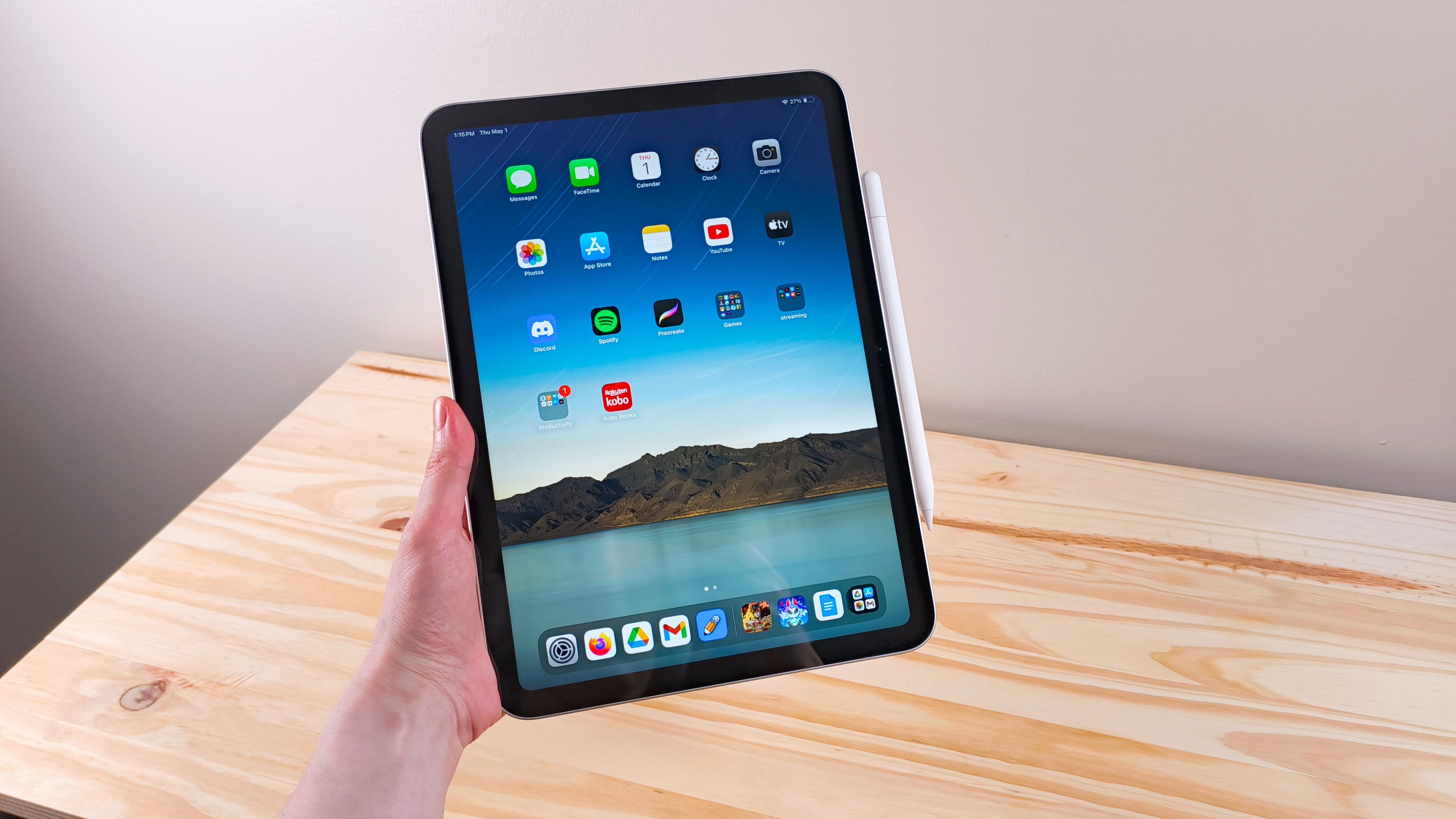 A hand holding up the iPad 11 showing the home screen