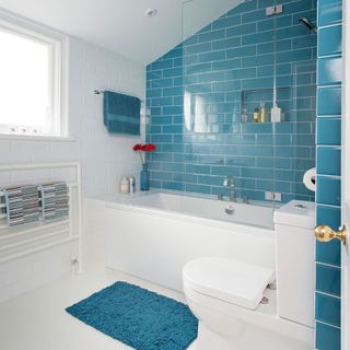 bathroom with teal blue tile wall and white bathtub