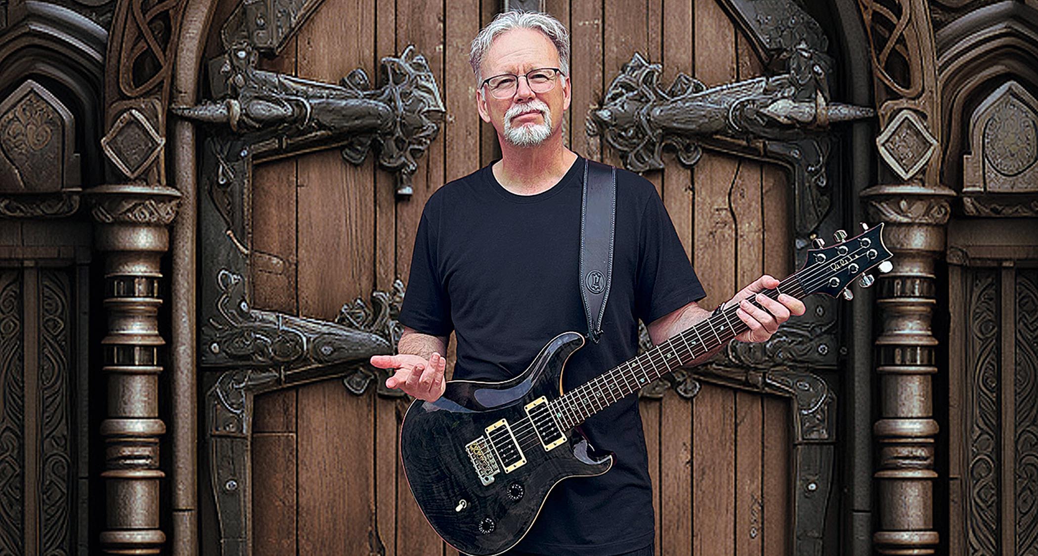 Chris Herin stands in front of an ornate old door with his PRS.