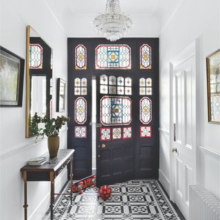 Interior of black front door with stained glass panels in the door itself, and in the surrounding panels