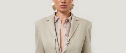 Model wearing a neutral shirt and suit jacket with gold chunky earrings sold at Karen Millen
